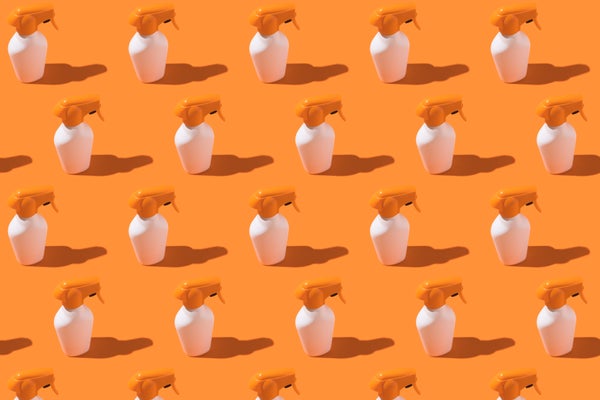 Pattern of white and orange bottles of sunscreen cream with spray on an orange background.